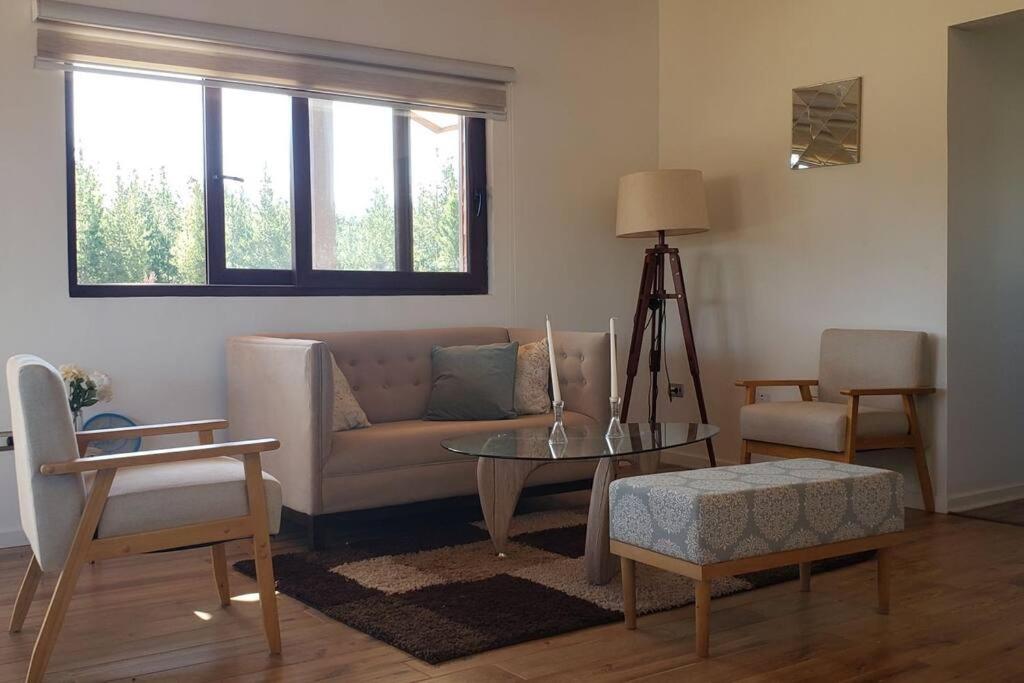 uma sala de estar com um sofá, uma mesa e cadeiras em Casa en condominio de parcelas em Yumbel