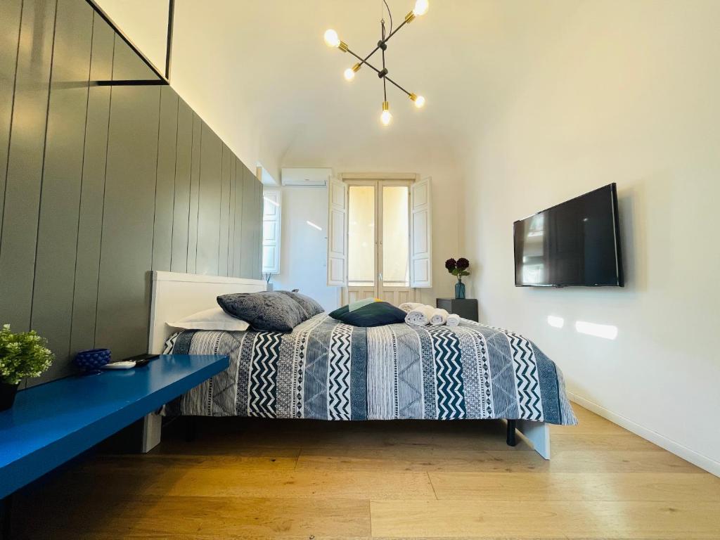 a bedroom with a bed and a tv on a wall at Dimora del Mercante in Catania
