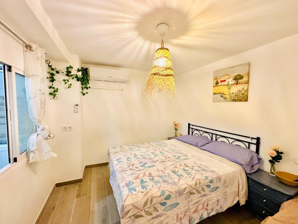 1 dormitorio con cama y lámpara de araña en JARA HOME Malaga Centro, en Málaga