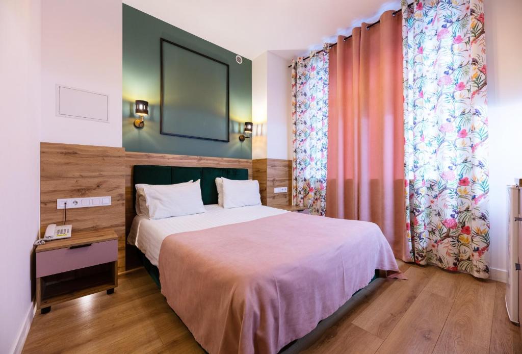 a bedroom with a large bed and a desk and curtains at Partner Guest House Baseina in Kyiv