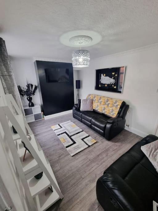 a living room with a black leather couch and stairs at Rise at the International Wall Belfast in Belfast