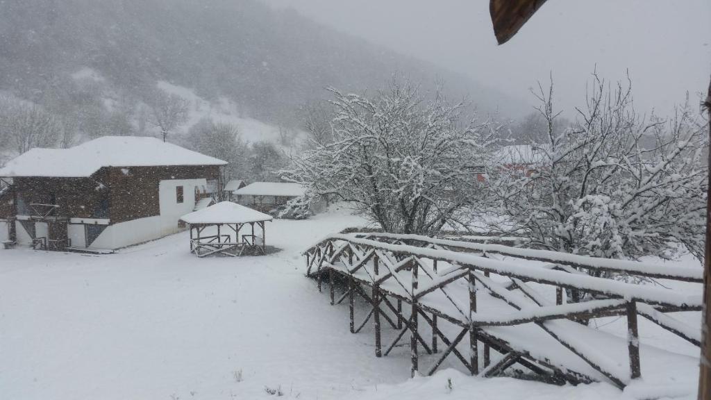 a snow covered yard with a bridge and a house at Etno Selo Stara Planina in Kalna