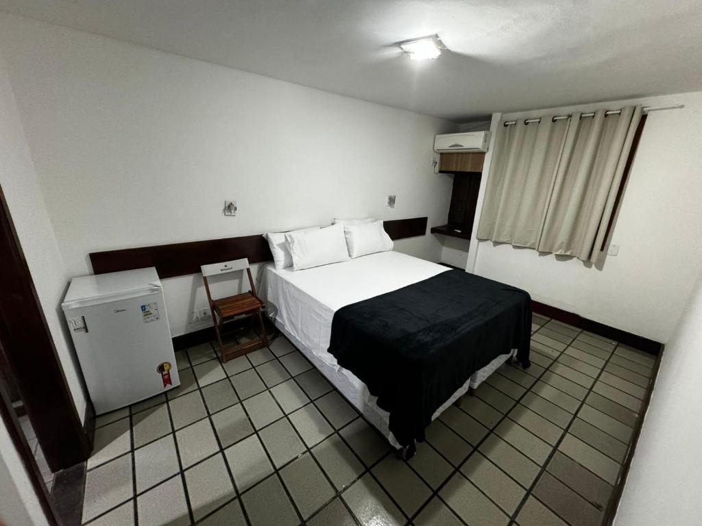 a bedroom with a bed and a small refrigerator at Suíte na Passarela do Álcool in Porto Seguro
