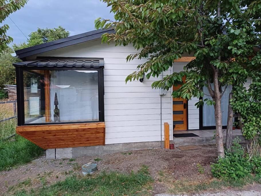 a small house with a window and a tree at Cabaña ñandú in Cochrane