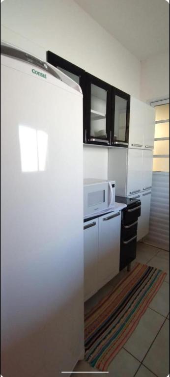 La cuisine est équipée d'un réfrigérateur blanc et d'un four micro-ondes. dans l'établissement Casa em Holambra- Sp, à Holambra