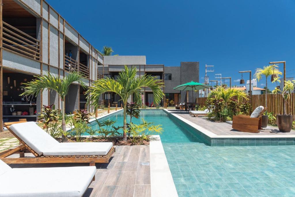 a swimming pool with chaise lounges and a resort at TOCA GAMBOA in Pôrto de Pedras