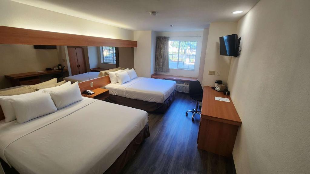 a hotel room with two beds and a television at SureStay by Best Western Sacramento South Natomas in Sacramento