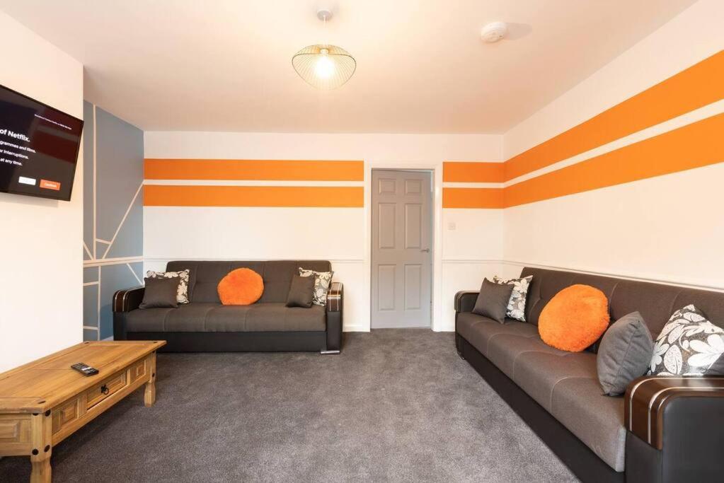 a living room with two couches and orange pillows at Origin - Close 2 city-centre, Shops, Netflix in Kirkstall