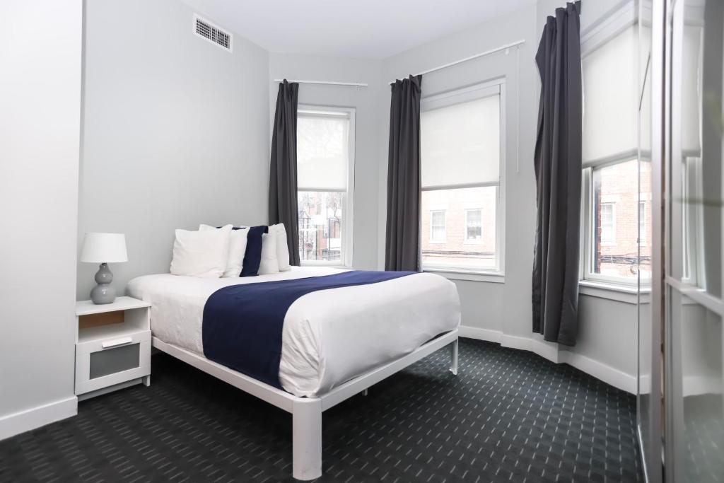 a white bedroom with a bed and two windows at Stylish Newbury Street Studio, #2 in Boston