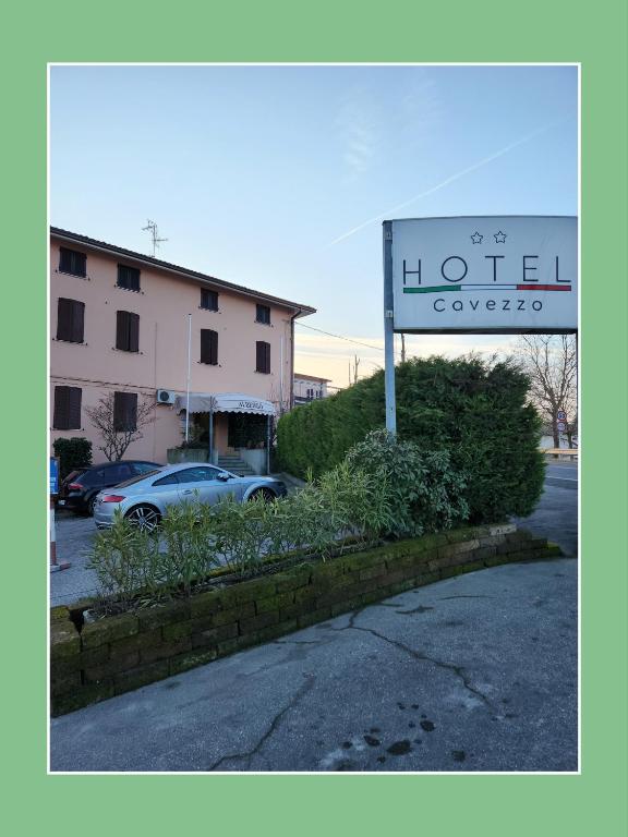 una señal para un hotel con coches estacionados en un estacionamiento en Hotel Cavezzo, en Cavezzo