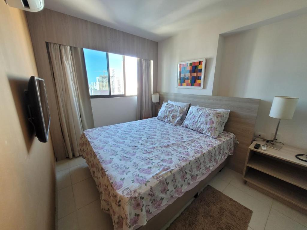 a small bedroom with a bed and a television at Flat Beach Class Recife in Recife