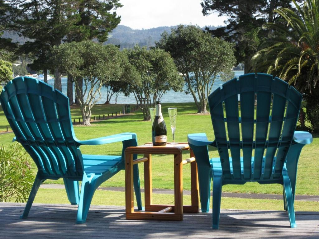 twee blauwe stoelen en een tafel met een fles wijn bij Pauanui Beach House Suntrap in Pauanui