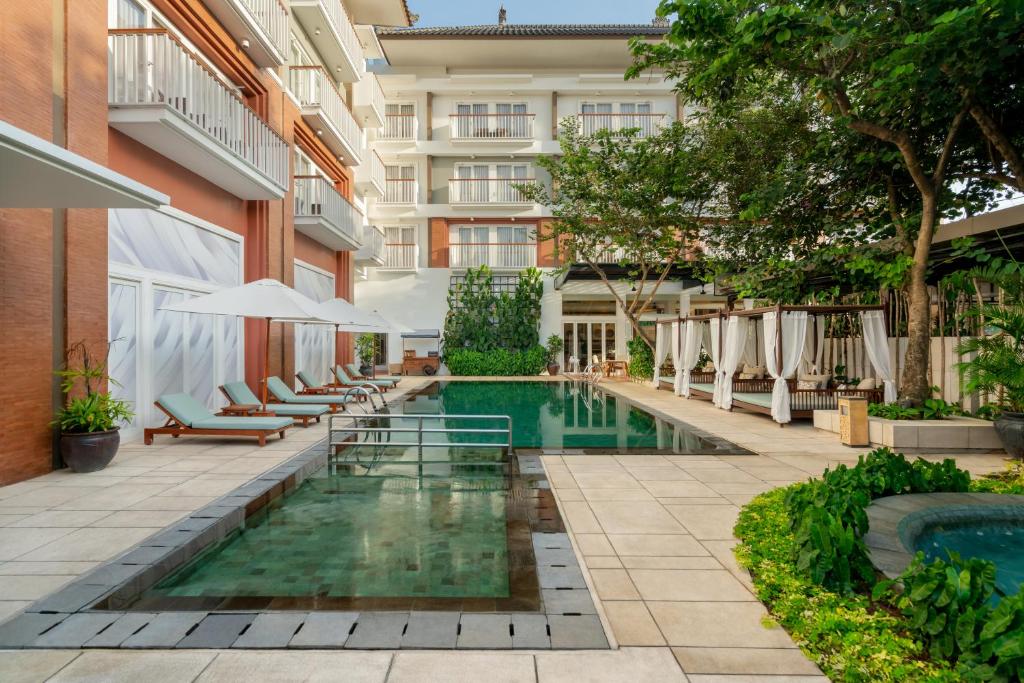 una piscina al aire libre en un hotel con mesas y sillas en Maison Aurelia Sanur, Bali - By Préférence en Sanur