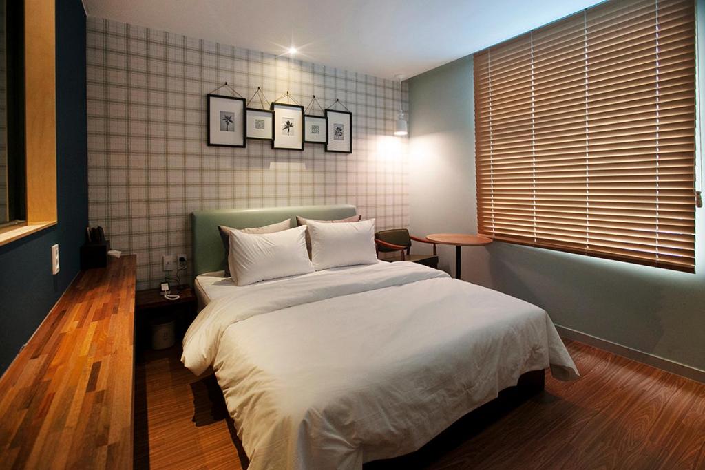 um quarto com uma cama grande e lençóis brancos em Brown Dot Hotel GimhaeEobang em Gimhae