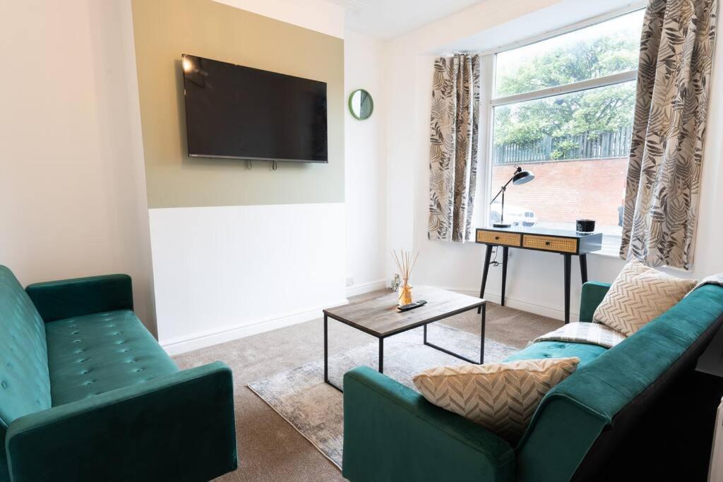 a living room with two green couches and a tv at Teal Retreat - Central Location - Free Parking, FastWifi, SmartTV with Netflix by Yoko Property in Redcar