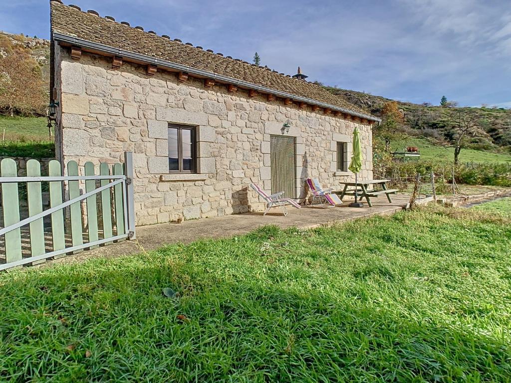 una casa de piedra con una valla y una mesa de picnic en Gîte authentique -Mont Lozère en Les Bondons