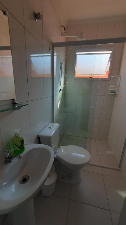 bagno bianco con lavandino e servizi igienici di AP Bertioga - Praia Indaia - Wi-Fi 500 Mega a Bertioga