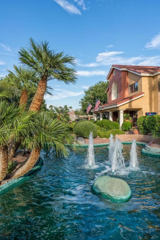 a fountain in the middle of a pond with palm trees at Westgate Flamingo Bay Resort in Las Vegas