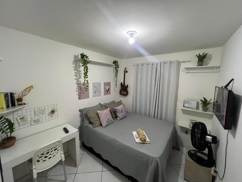 a bedroom with a bed and a desk and a television at Quarto Encantado in João Pessoa