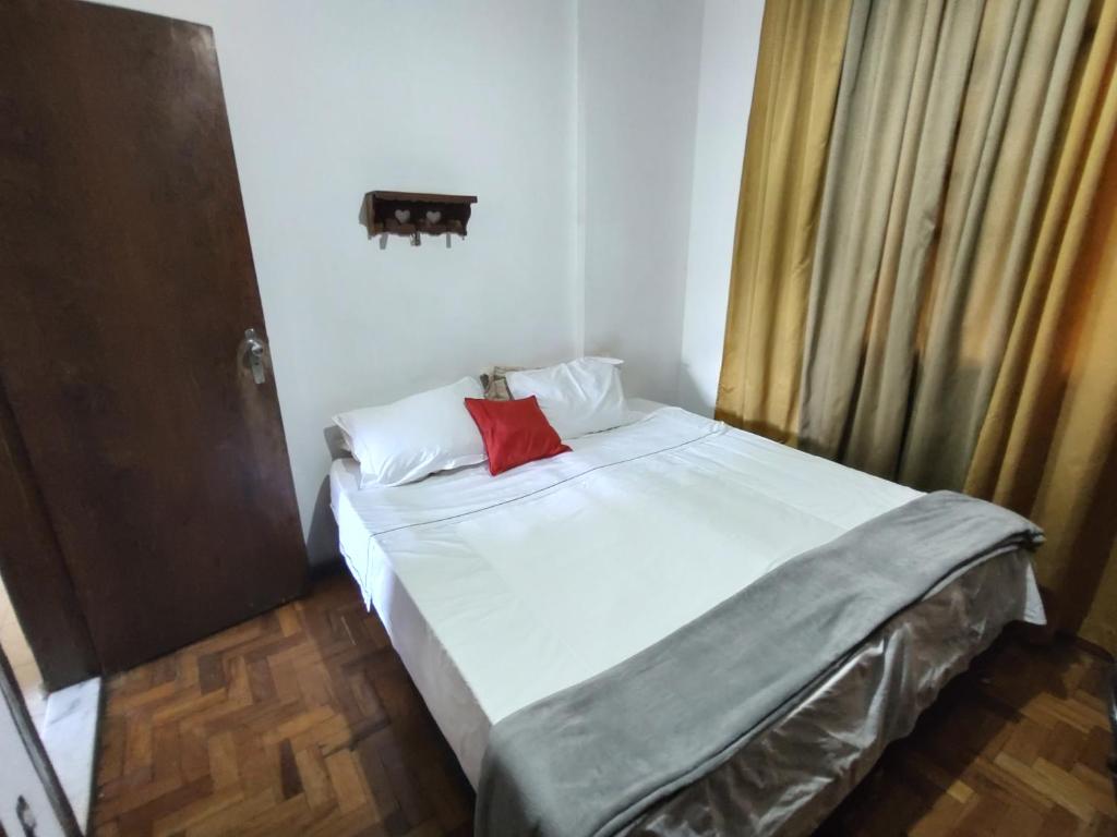 um quarto com uma cama com uma almofada vermelha em Quarto próximo da Savassi. em Belo Horizonte