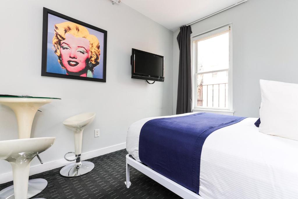 Cozy & Stylish Newbury Street Studio, #9 في بوسطن: غرفة نوم مع سرير وتلفزيون على الحائط