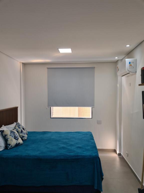 une chambre avec un lit bleu et une fenêtre dans l'établissement Loft em prédio em frente à praia, à Santos