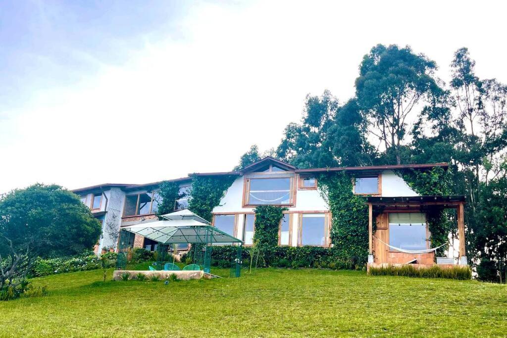 une maison avec une pelouse devant elle dans l'établissement Gran CASA FINCA embalse de Tominé wi-fi, tv, BBQ, à Sesquilé