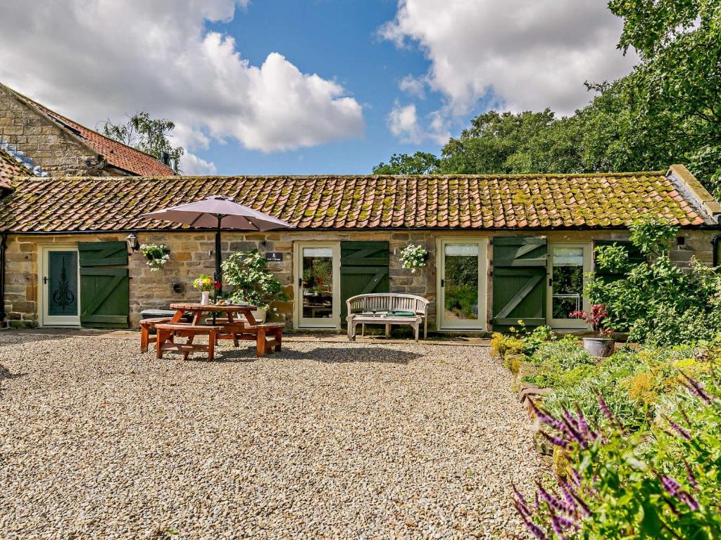 a patio with a table and an umbrella in front of a house at 1 Bed in Helmsley 93100 in Chop Gate