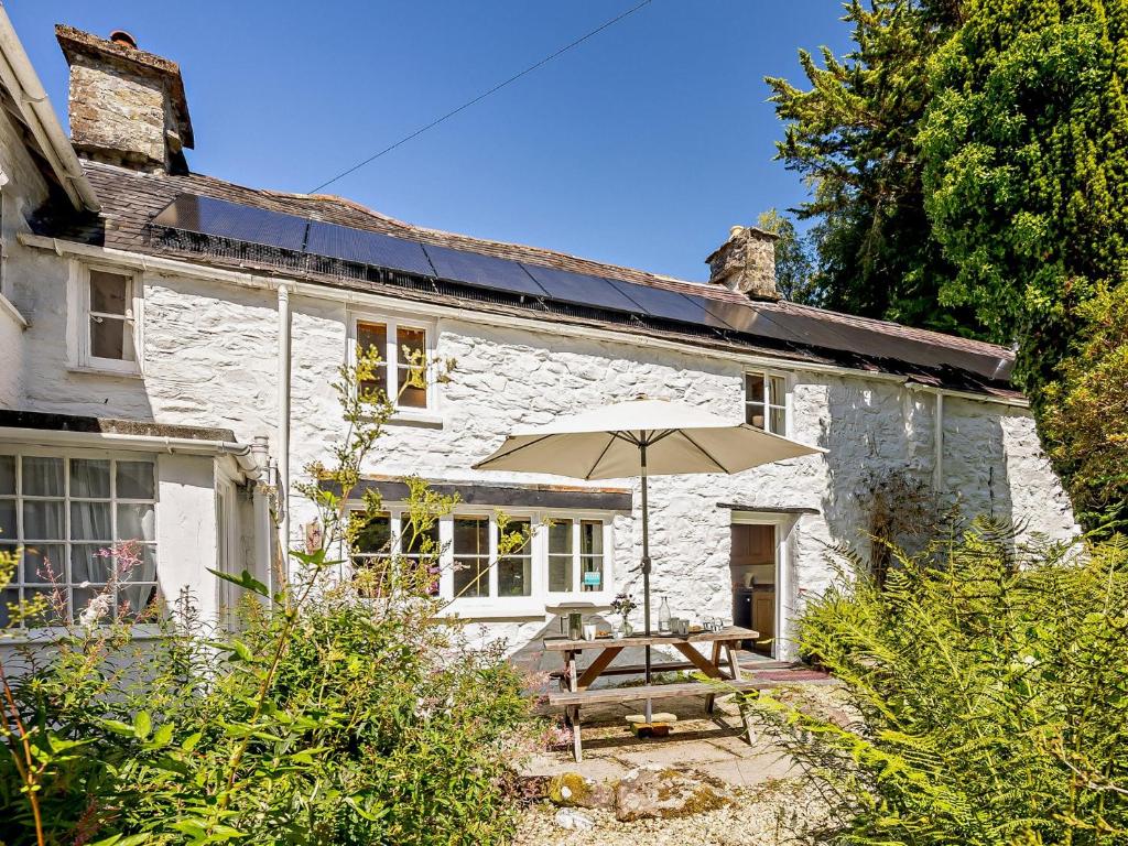 a white cottage with a wooden table and an umbrella at 2 Bed in Machynlleth 93082 in Cemmaes