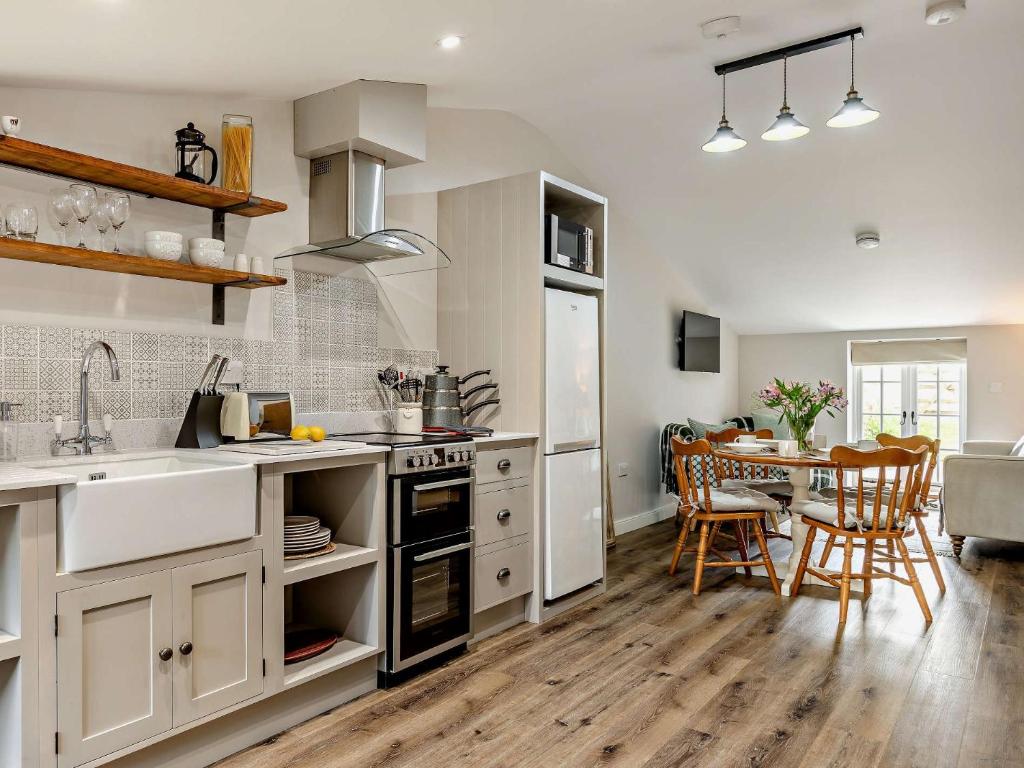 una cocina con armarios blancos y una mesa con sillas. en 2 Bed in Barnstaple 5mls N 93025, en Chapelton