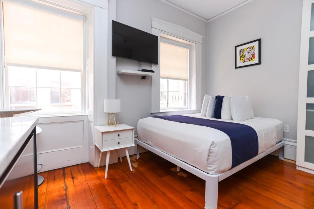 a white bedroom with a bed and two windows at Charming & Stylish Studio on Beacon Hill #12 in Boston