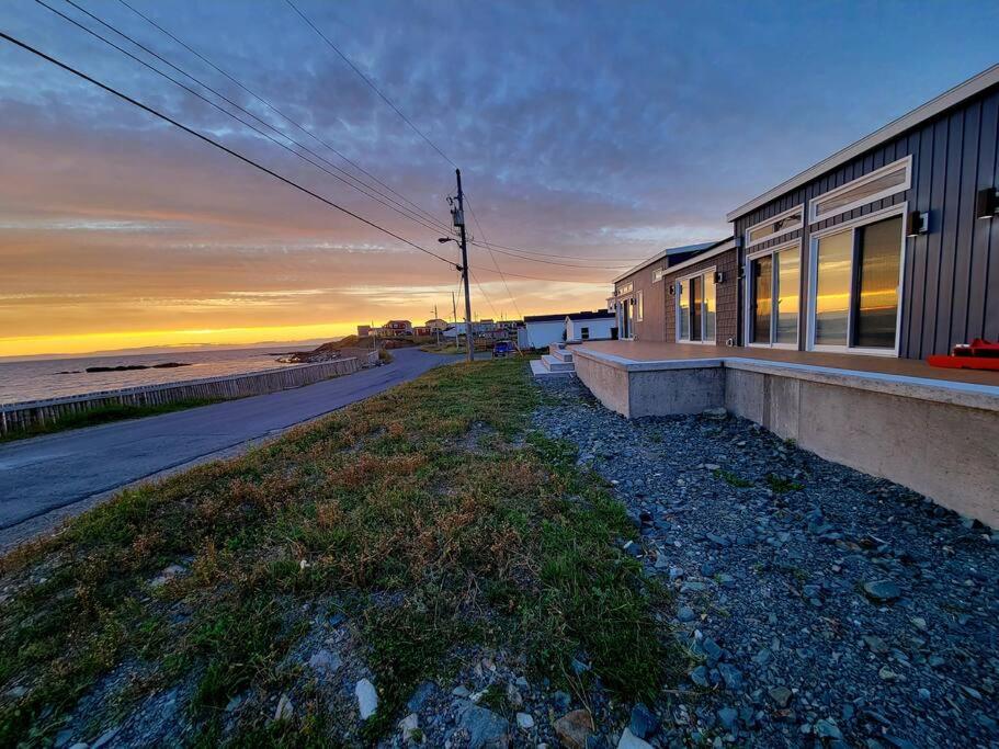 a building on the side of a beach at sunset at 2 Bedroom 2 Bathroom Oceanfront Oasis in Bonavista