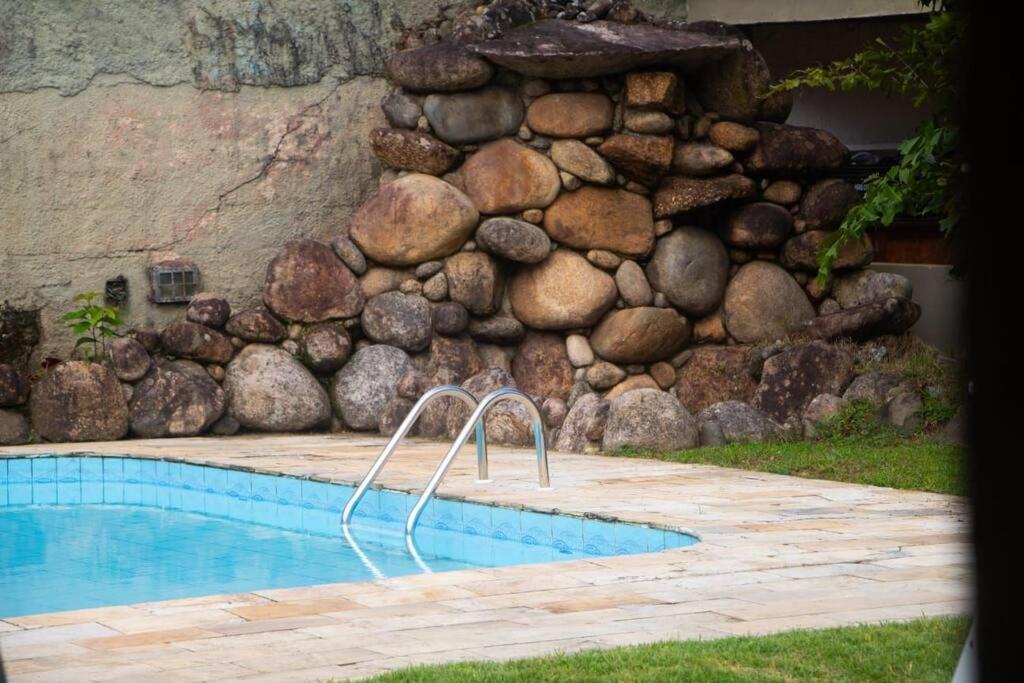 a rock retaining wall next to a swimming pool at Villa Tavares - casa com piscina na praia da Lagoinha in Ubatuba