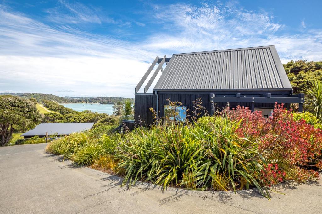 una casa negra con flores delante en The Guest House at Te Whau Retreat en Omiha