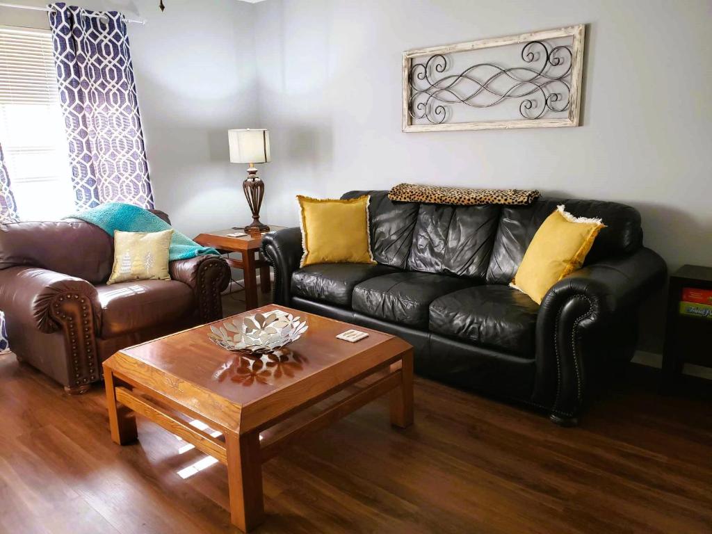 a living room with a black leather couch and a coffee table at Midtown Southern Charm in Tyler