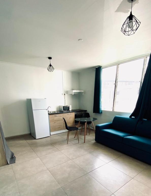 een woonkamer met een blauwe bank en een tafel bij Little urban idéal pour les séjours de moyenne durée proche de tout in Pointe-à-Pitre