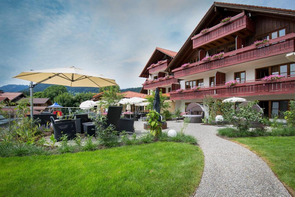 a building with an umbrella and tables and chairs at Familien- und Wellnesshotel "Viktoria" in Oberstdorf