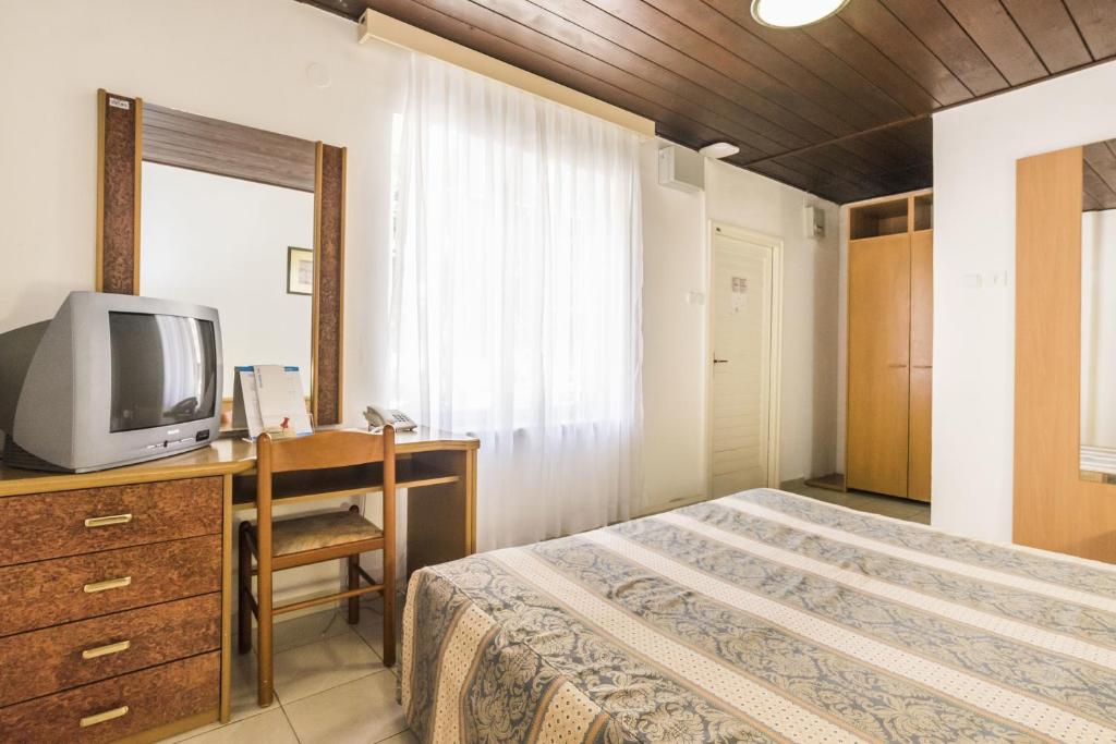 una camera con letto e scrivania con TV di Rooms Savudrija Plava Laguna a Savudrija