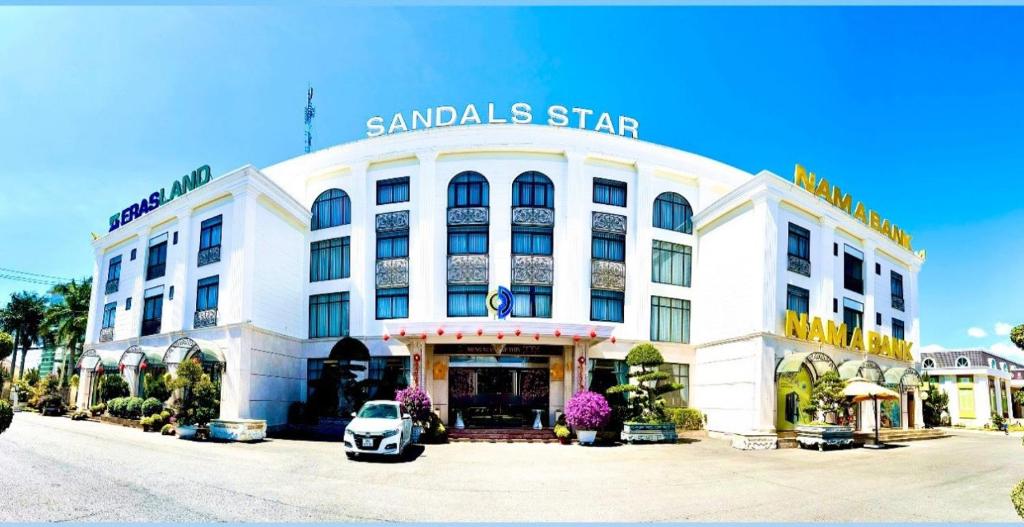 Un bâtiment blanc avec une voiture garée devant. dans l'établissement Sandals Star Hotel, à Ðưc Trọng