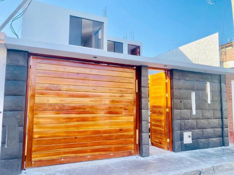 una puerta de madera de garaje en el lateral de una casa en Acogedora casa en Pisco a 20 min de paracas, en Pisco