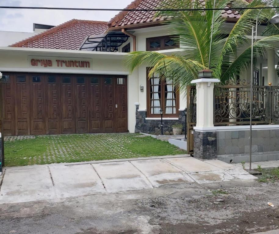 a house with a palm tree in front of a garage at Guesthouse Syariah Griya Truntum in Lawean