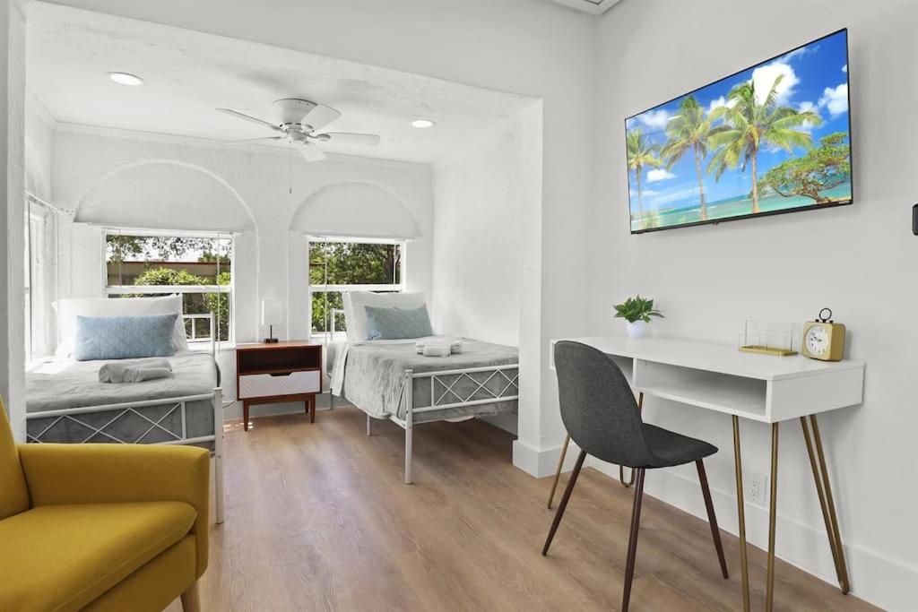 a white room with a bed and a desk and a couch at Palm Wave Says - Designers Stay - No Extra Fees in West Palm Beach