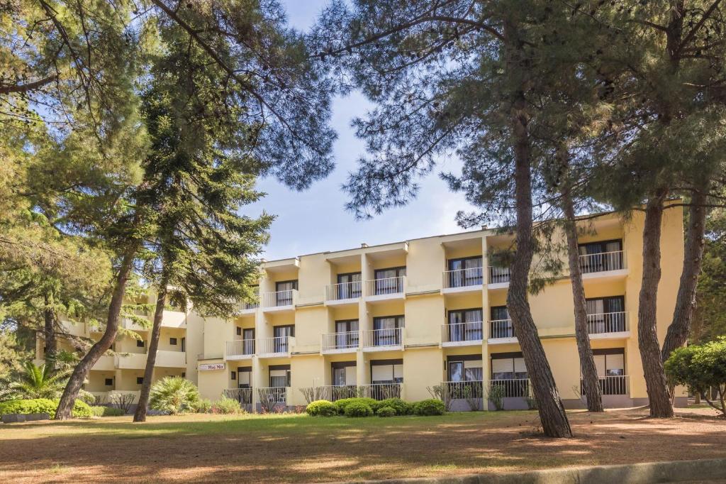 um edifício de apartamentos com árvores em primeiro plano em Rooms Savudrija Plava Laguna em Savudrija
