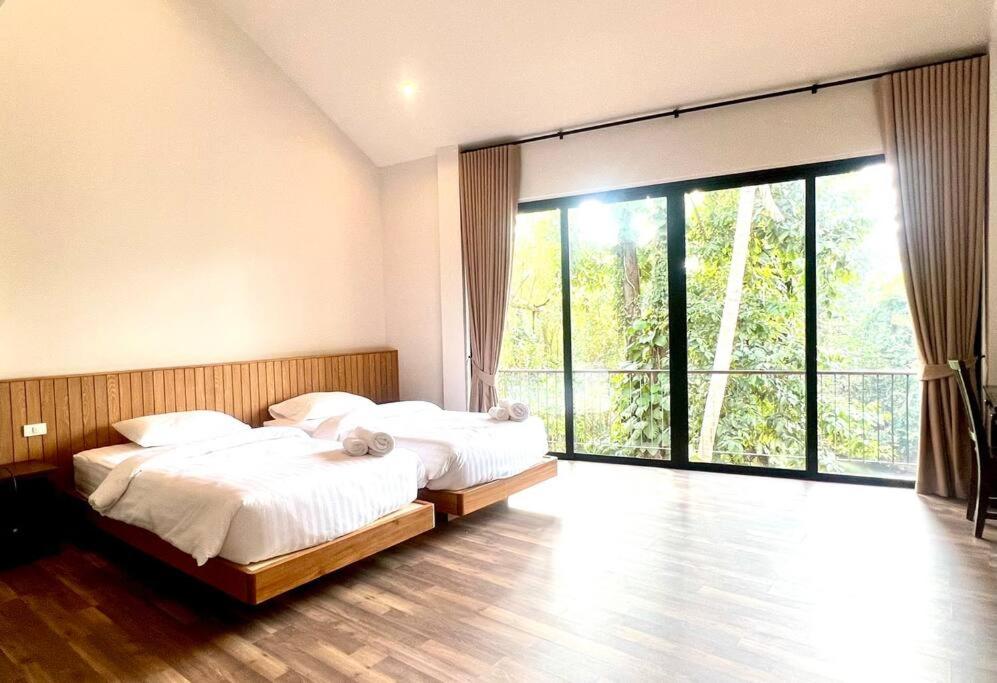 a bedroom with two beds and a large window at Villa 173 - Two bedroom private villa in Ban Pak Chong Noi