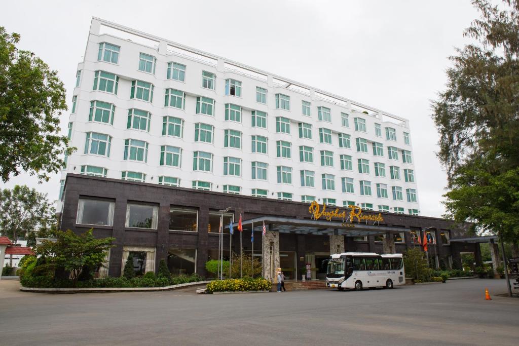 un autobús está estacionado frente a un edificio en Van Phat Riverside Hotel, en Can Tho