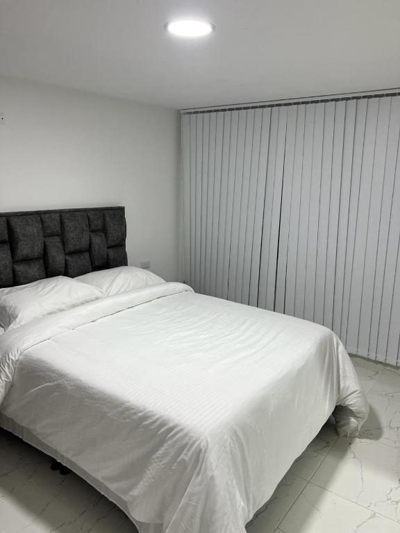 a bedroom with a large white bed in it at AVENIDA SANTANDER EL TRIANGULO HABITACION 4 in Manizales