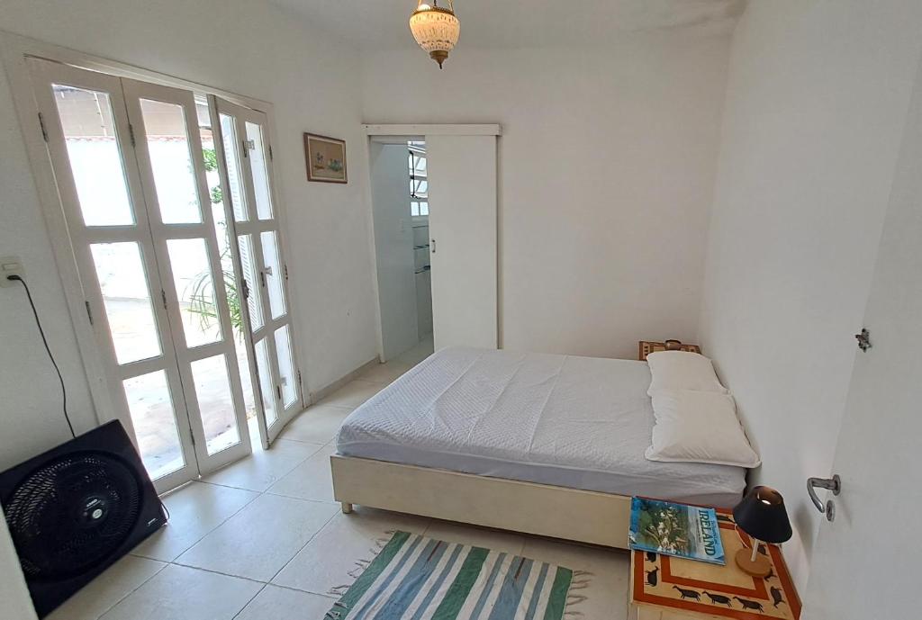 a small bedroom with a bed and a balcony at Suíte Beach Host - Praia Pernambuco in Guarujá