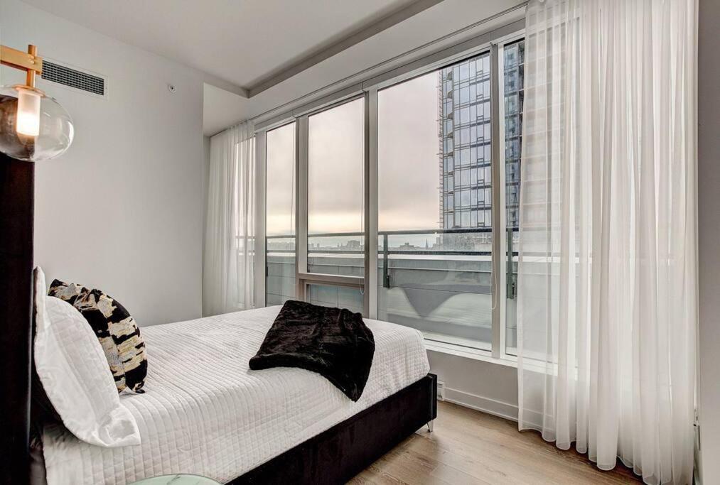 a bedroom with a bed and a large window at Beautiful Downtown condo with Pool and Parking in Montréal