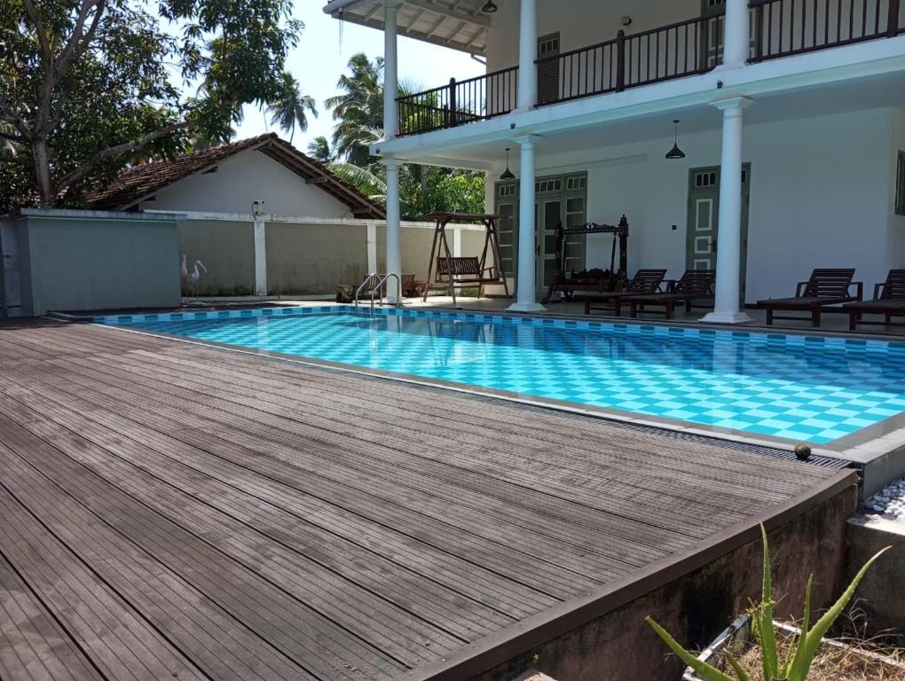 a swimming pool with a wooden deck next to a house at Nade Villas Ahungalla in Ahungalla
