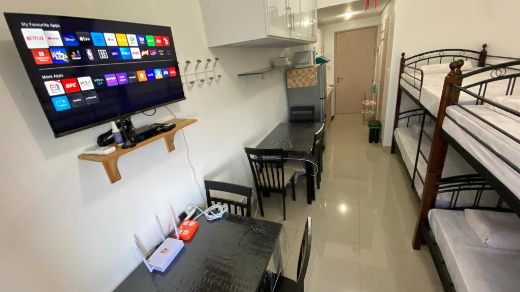 Habitación con mesa y TV en la pared. en Fully-furnished studio-type SMDC, en Dasmariñas